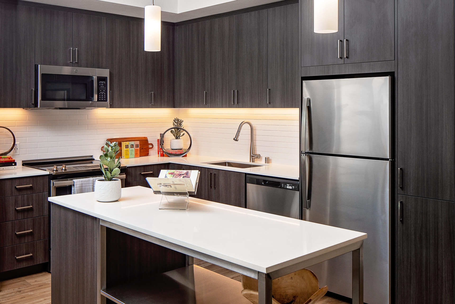 Kitchen featuring Stainless Steel appliances, quartz countertops, and a backsplash with elegant lighting and designer hardware fixtures.