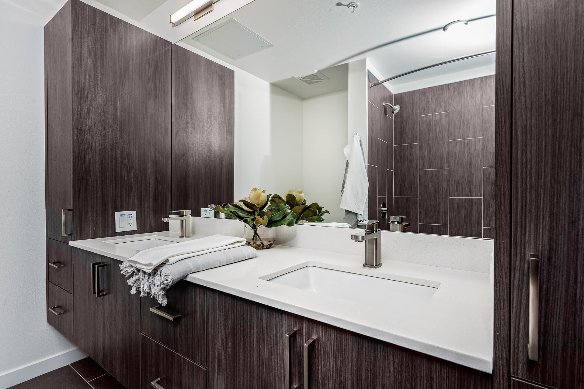 A bathroom featuring custom-built cabinetry, a double sink, and stunning lighting fixtures.