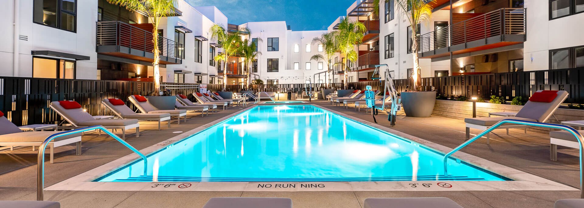 Legacy at Hayward's outdoor pool area, surrounded by lush palm trees and enclosed by the surrounding buildings.